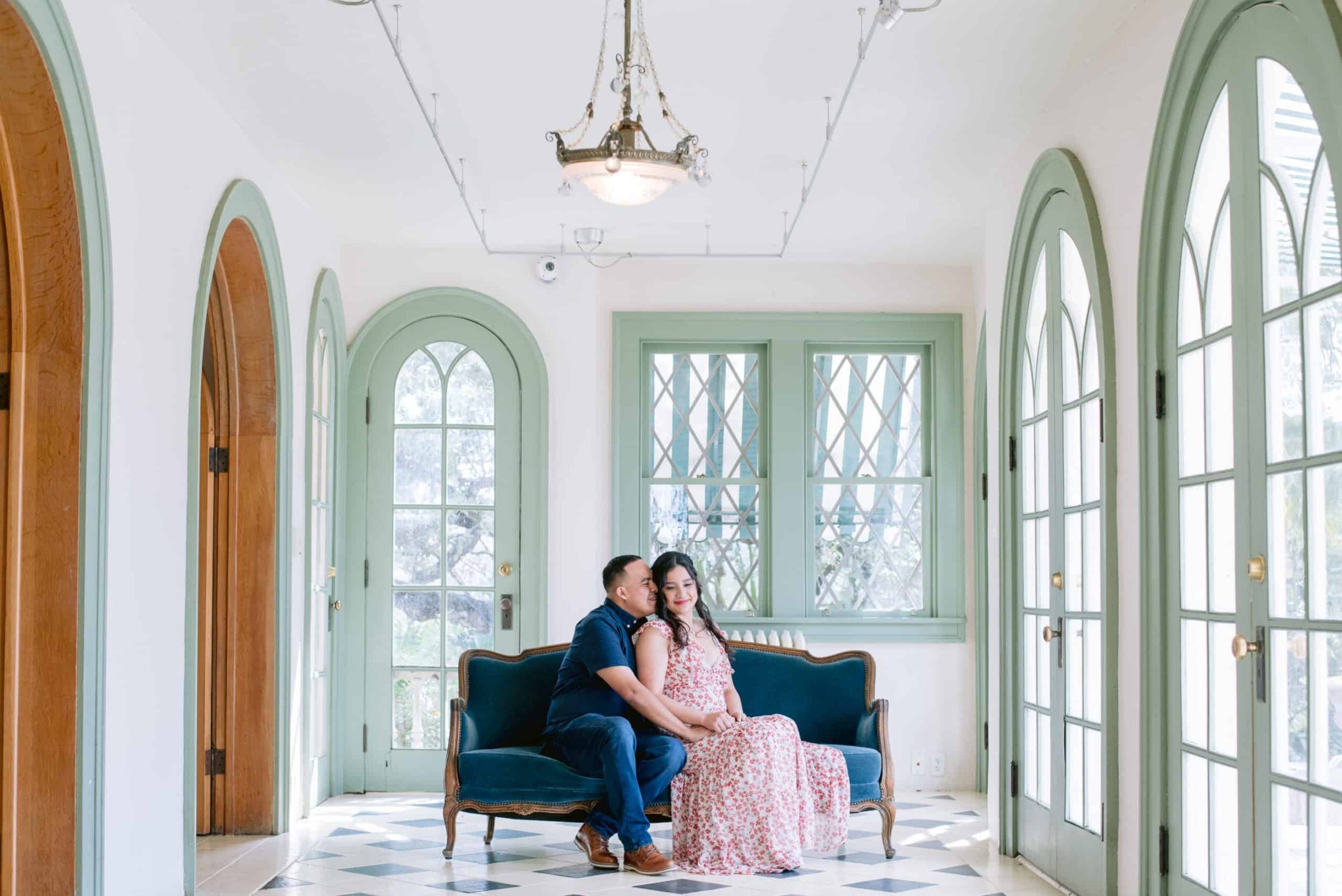 Couple nuzzles each other sitting on a couch at laguna gloria in austin texas