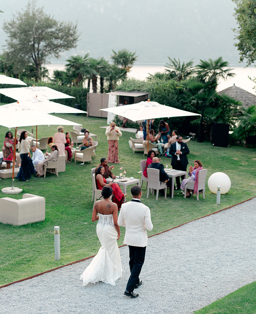Guests gathering for cocktail hour on the lawn overlooking Lake Como at Villa Lario Resort in Mandello del Lario during an intimate destination wedding.